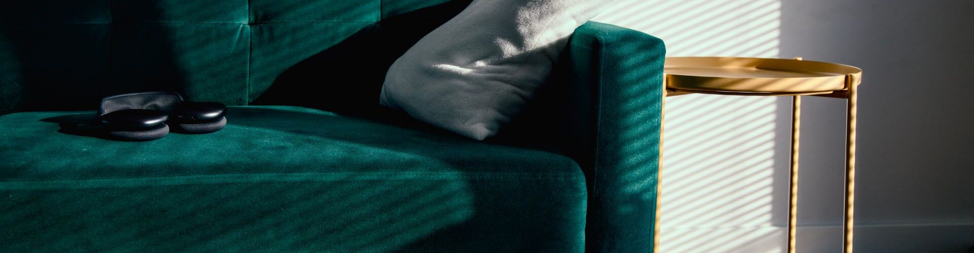 Grøn velour-sofa i en stue med sollys