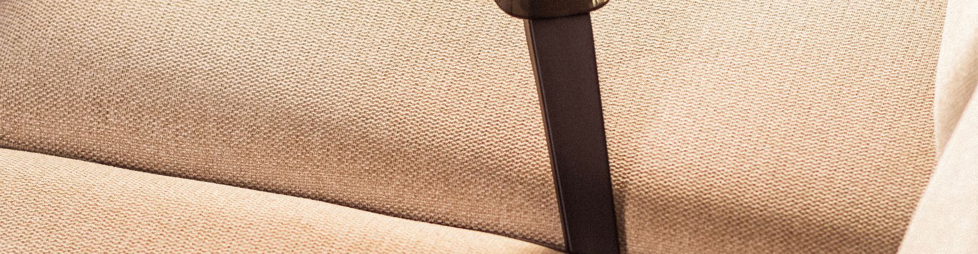 Støvsugning af en beige sofa med håndstøvsuger